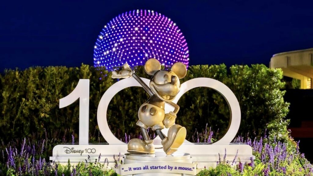 hacks to genie plus: mickey statue in front of 100 year sign and the epcot spaceship earth ball at night.