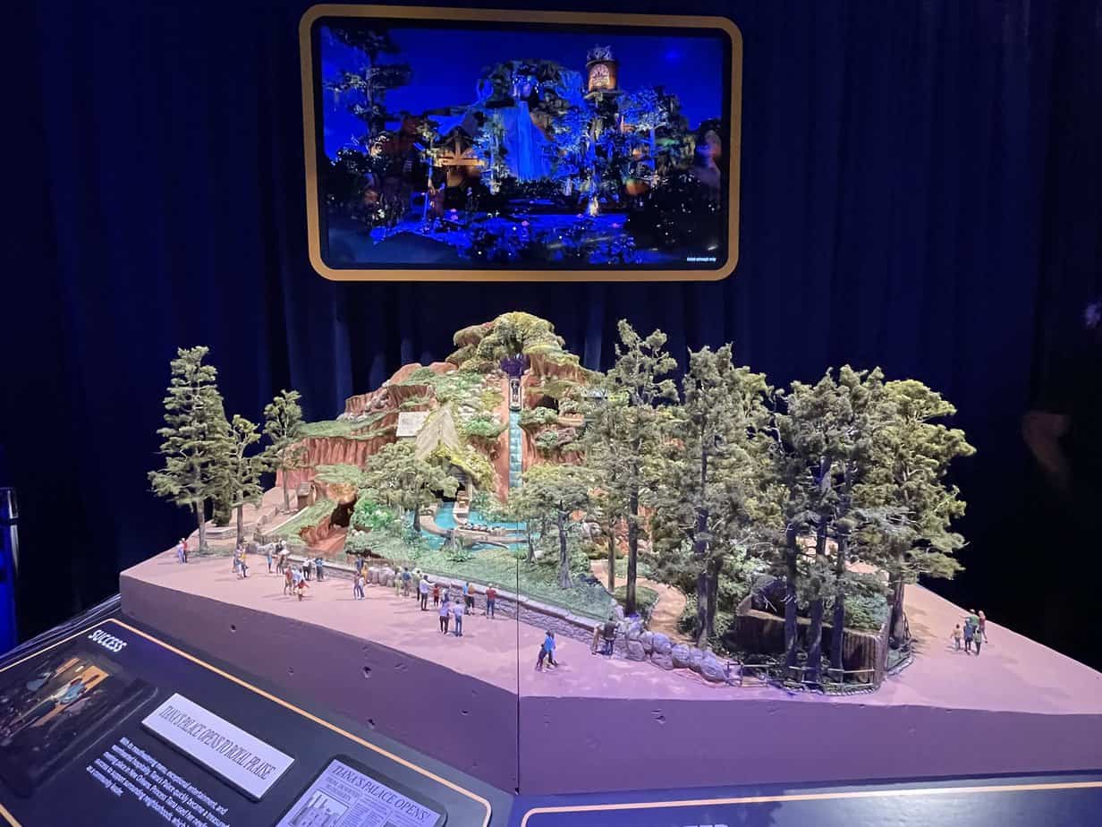 Tiana's Bayou Adventure model on display at D23 Expo with a screen behind it showing what the attraction will look like at night. 